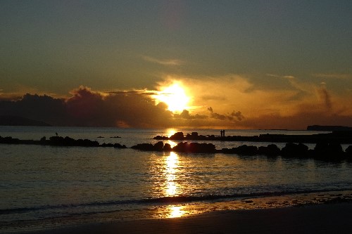 Lovers holding eachother as the soaked in a powerful sunset
