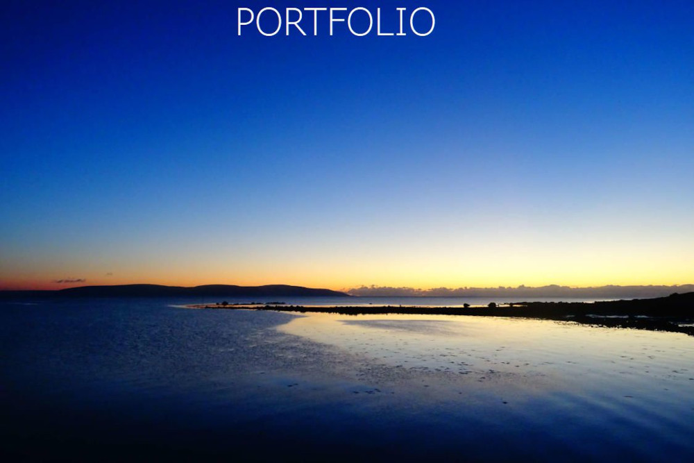Navigation image for the Porfolio page- of a deep blue & gold sunset over Bearna, Galway