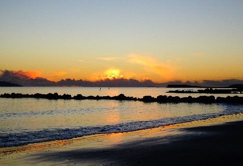 A paddle board in the distance, looking out over a firey sunset sky
