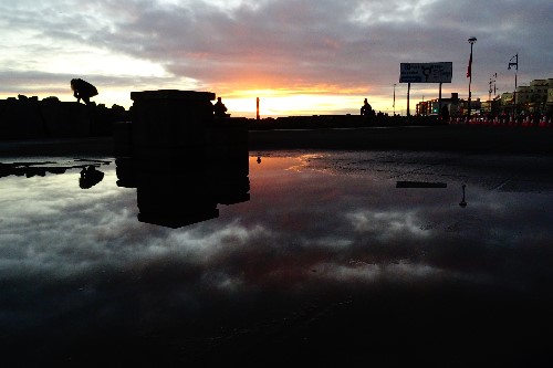 Reflection in a puddle of people enjoying the views of the ocean
