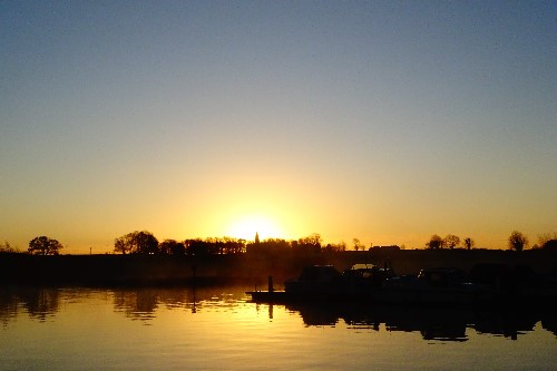 The sun rising directly behind a church Cathedral in Tipperary, reflecting on Lough Derg