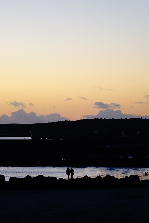 Two people walking in the distance captured directly in between surrounding silhouette's